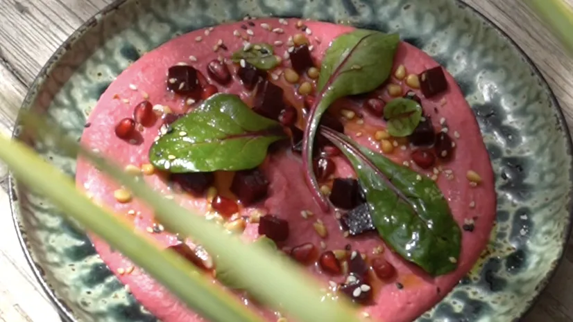 Beetroot hummus on a glazed plate, shot in daylight.
