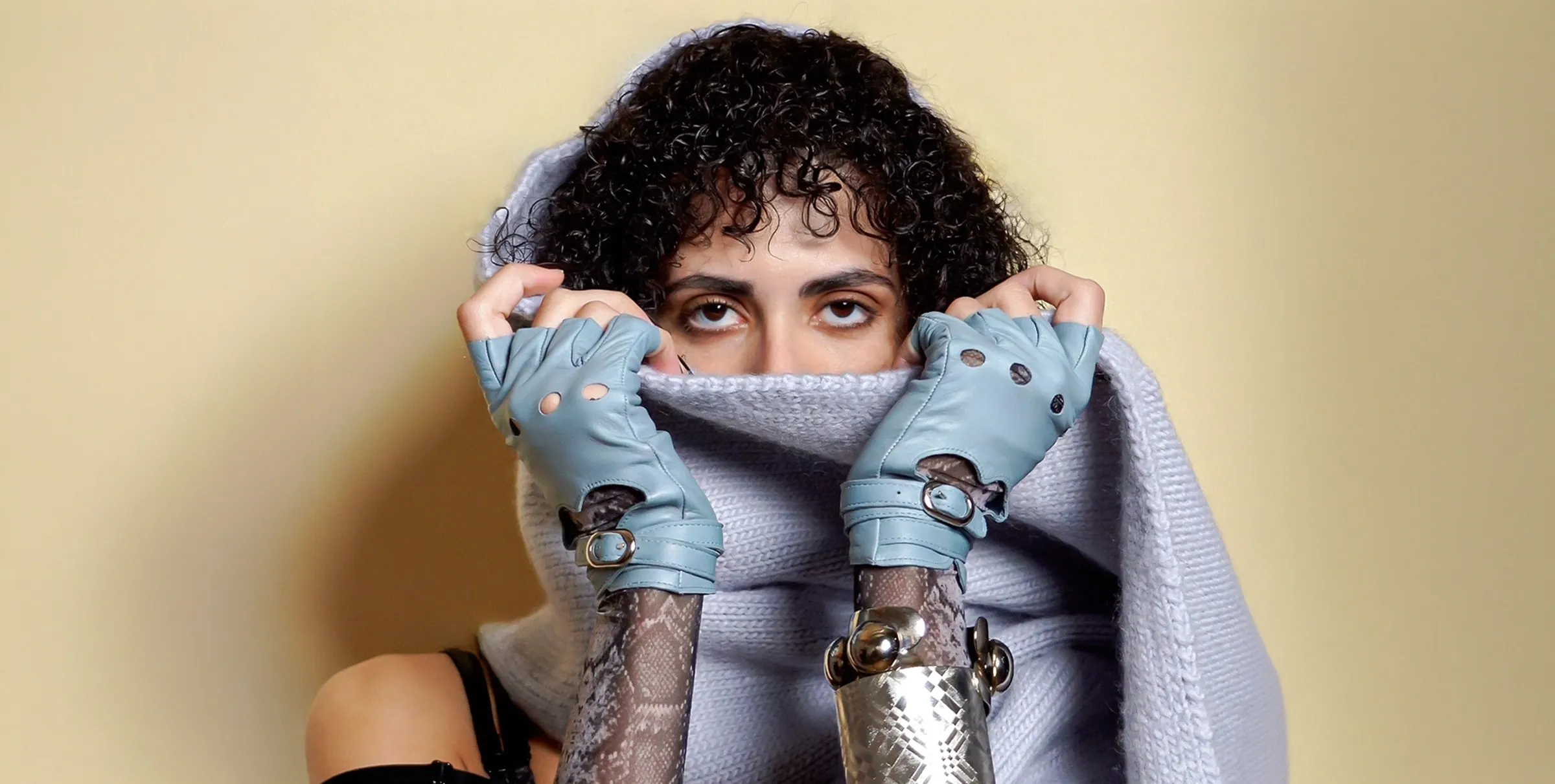 Gloves and a metal cuff, shot against a yellow backdrop.